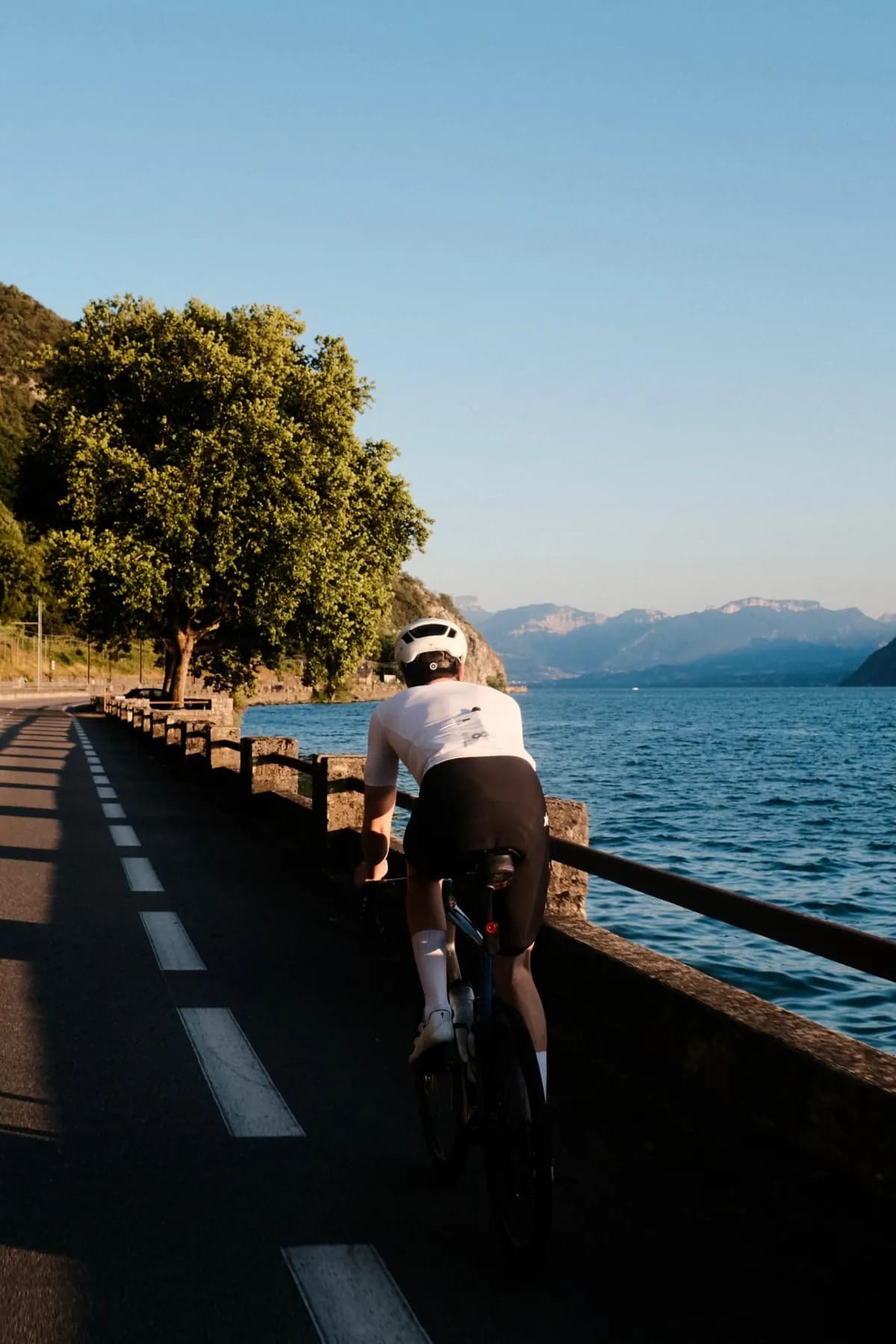 Un cycliste seul le long d'un lac de montagne, au soleil du soir.